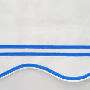May include: White fabric with a scalloped edge and two blue stripes. The fabric has a subtle sheen.