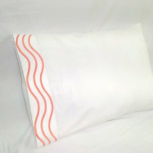 May include: White pillowcase with a coral coloured wavy border.