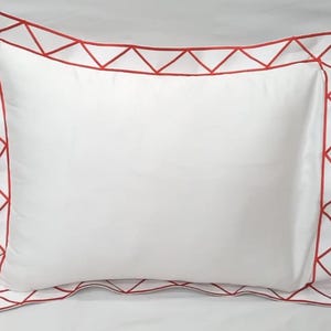 Puede incluir: Funda de almohada blanca con un borde rojo de patrón geométrico.