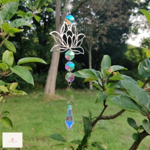 May include: A silver metal lotus flower suncatcher with iridescent crystal beads and a teardrop-shaped crystal hanging from the bottom.