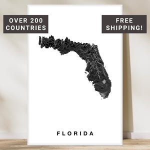 May include: A monochrome topographic map of Florida, with the state's name in a bold font at the bottom. The image includes text that reads "OVER 200 COUNTRIES" and "FREE SHIPPING!"