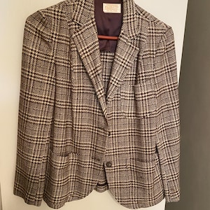 Op de afbeelding: Een bruin en wit geruit blazer met een enkele knoopsluiting. De blazer heeft een bruine voering en een label met de tekst "Fashioncraft" aan de binnenkant.
