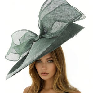 Puede incluir: Un sombrero verde elegante con un gran lazo. El sombrero presenta un ala ancha y un dise&ntilde;o estructurado, ideal para ocasiones especiales. El color es un verde apagado y sofisticado.