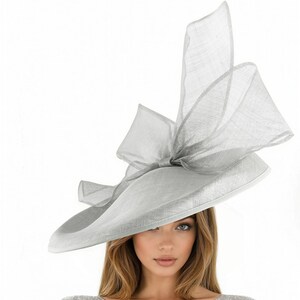 Puede incluir: Un sombrero gris claro de ala ancha con un gran lazo y detalles decorativos. El sombrero est&aacute; hecho de una tela ligera y es adecuado para eventos formales. El ala del sombrero mide aproximadamente 35.5 cm de di&aacute;metro.