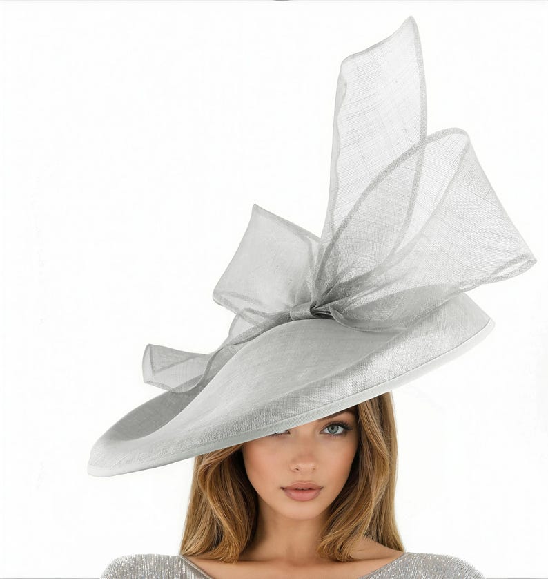 Puede incluir: Un sombrero gris claro de ala ancha con un gran lazo y detalles decorativos. El sombrero est&aacute; hecho de una tela ligera y es adecuado para eventos formales. El ala del sombrero mide aproximadamente 35.5 cm de di&aacute;metro.