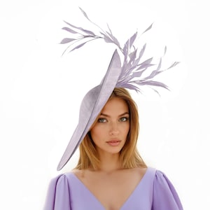 Może przedstawiać: Jasnofioletowy kapelusz z szerokim rondem i ozdobą z piór. Osoba nosi pasującą fioletową sukienkę. Stylowy dodatek na specjalne okazje.