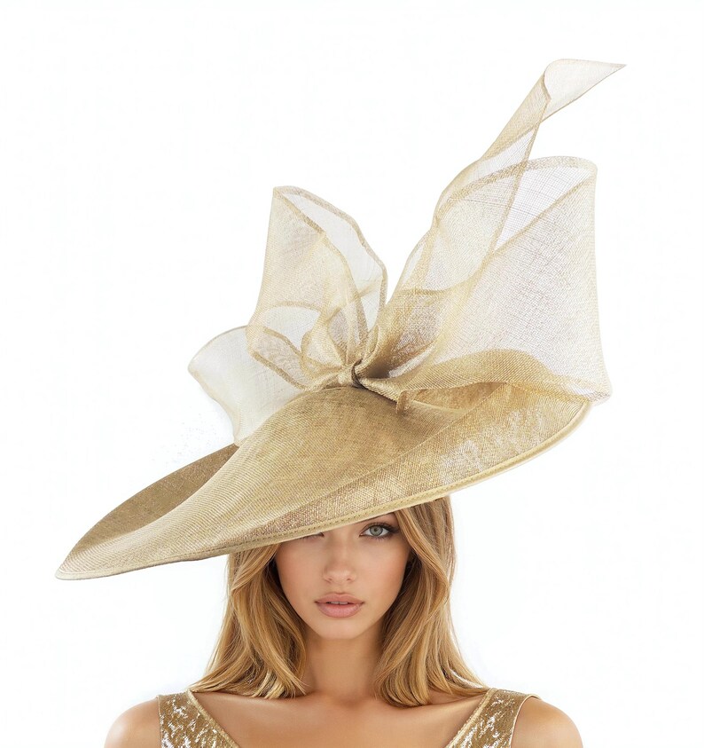 Puede incluir: Un sombrero grande, de color dorado, con ala ancha y lazo decorativo. El sombrero est&aacute; hecho de un material tejido y tiene un lazo transparente y aireado en la parte superior. Ideal para eventos formales.