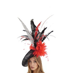 May include: A black hat with a wide brim, adorned with a vibrant arrangement of red, black, and gray feathers and a large red flower. The hat is designed for special occasions and events.