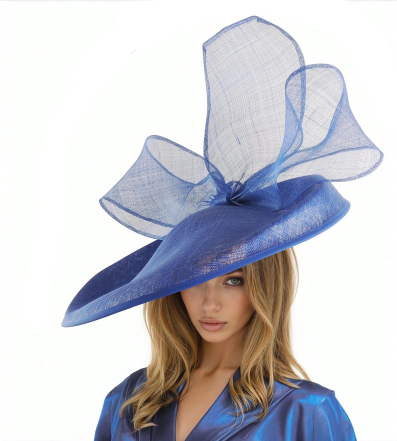 Puede incluir: Un llamativo sombrero azul con ala ancha y un acento fluido y transparente. El dise&ntilde;o del sombrero presenta una base estructurada y una parte superior delicada y aireada, creando un look dram&aacute;tico y elegante. Un accesorio de moda llamativo.