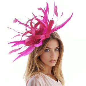 May include: A vibrant fuchsia headpiece with feathers and decorative elements. The headpiece is worn by a person with long blonde hair and a light pink top. The headpiece is likely for a special occasion.