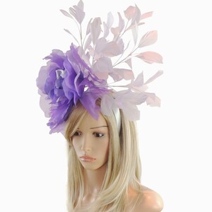 Puede incluir: Una diadema de flores de color morado y blanco con plumas. La diadema est&aacute; hecha de sat&eacute;n y tiene un dise&ntilde;o delicado y femenino.
