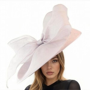 Puede incluir: Un sombrero lila claro con un gran lazo. El sombrero tiene un ala ancha y est&aacute; hecho de una tela transparente y ligera. El lazo es el punto focal, agregando un toque de elegancia. Adecuado para ocasiones especiales.