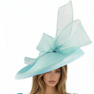 Puede incluir: Un sombrero azul claro de ala ancha con un gran lazo. El sombrero tiene una copa redonda y un ribete azul claro contrastante. El lazo est&aacute; hecho de una tela transparente, agregando un toque delicado. Este elegante sombrero es adecuado para ocasiones especiales.