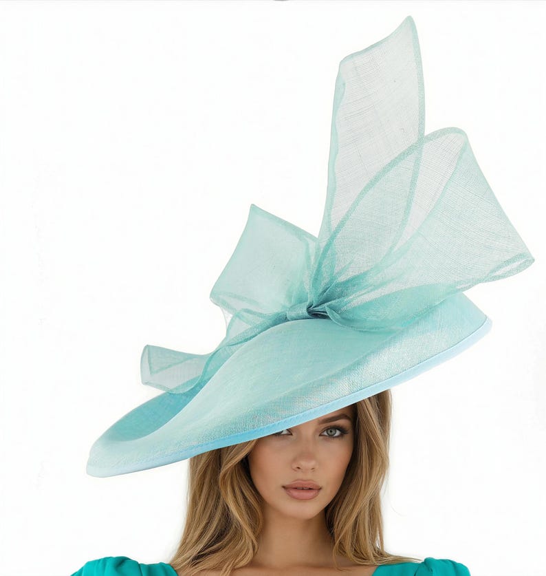 Puede incluir: Un sombrero azul claro de ala ancha con un gran lazo. El sombrero tiene una copa redonda y un ribete azul claro contrastante. El lazo est&aacute; hecho de una tela transparente, agregando un toque delicado. Este elegante sombrero es adecuado para ocasiones especiales.