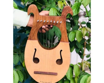 May include: A wooden lyre with a light brown body and dark brown accents. The lyre has a round sound hole and a bridge with strings.