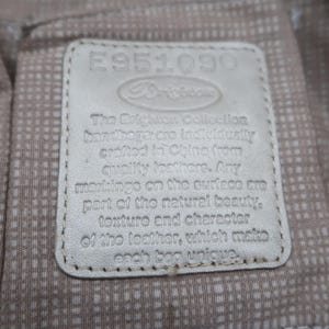 Puede incluir: Una etiqueta de cuero blanco con el texto "E951090" y "The Dilighuais Collection handbags are individually crafted in China from quality leathers. Any markings on the surface are part of the natural beauty, texture and character of the leather, which makes each bag unique."