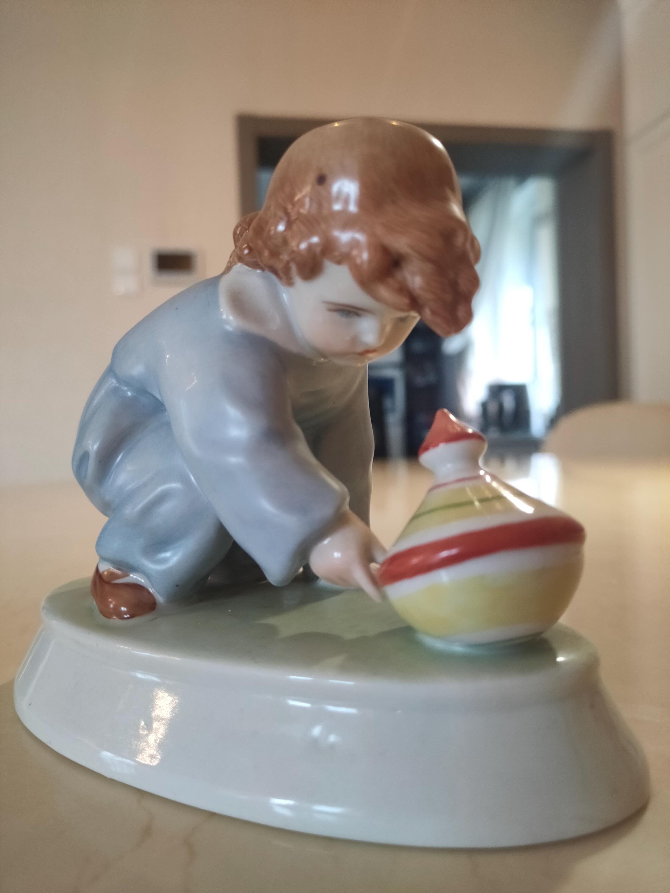Porseleinen beeldje "Jongen met tol". Vervaardigd door ZSOLNAY (Hongarije)