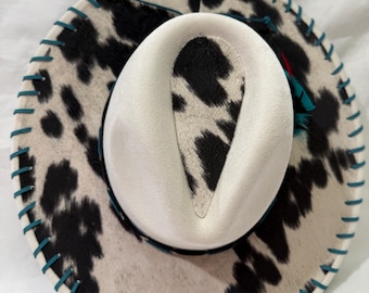 Red wide brim hat, black/white cowhide fabric, flowers burned on brim, black band, red/black feathers, black leather lacing.