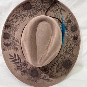 Custom hand burned mocha wide brim hat, sunflowers burned all around brim, brown leather hat band with turquoise feathers.