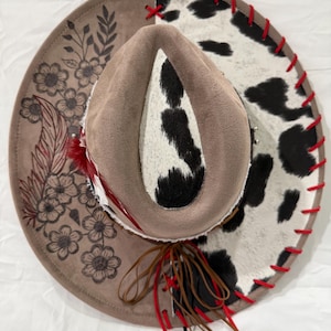 Mocha Wide Brim Hat: Black/White Cowhide Fabric With Red Leather Lacing And Flowers/Feather Burned On Brim Brown Leather Band With Feathers
