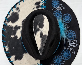 Handbränd hatt med bred brätte, svart: Kohudtyg, lädersnörning och turkosa blommor målade på brättet, turkos hattband med fjädrar
