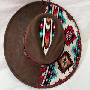Wide brim brown hat, Aztec fabric with red leather lacing and arrow burned on brim, red/leather hat bands with red feathers.