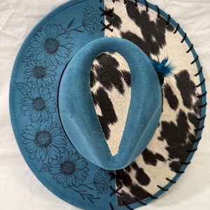Custom hand burned ocean blue wide brim hat, black/white cowhide fabric with black leather lacing and flowers burned on brim.