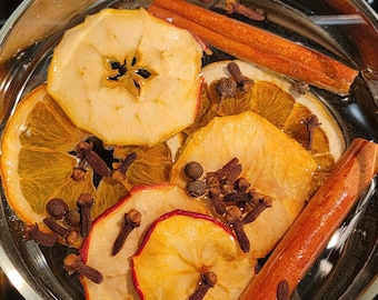 May include: A glass bowl filled with water and various ingredients for a potpourri, including dried apple slices, orange slices, cinnamon sticks, and cloves.