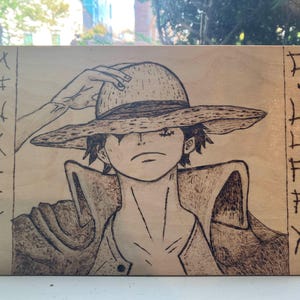 May include: A wood-burned image of a character with a straw hat, wearing a long coat. The background is a light wood with a pattern of lines on the left and right sides.
