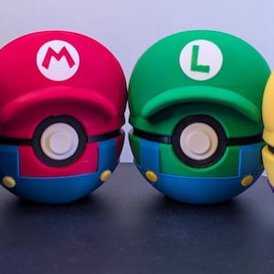 May include: Four spherical containers designed to resemble character hats, each featuring a central circular button. The colors include purple with a yellow L, red with a white M, green with a white L, and yellow with a blue W, all with matching brims.