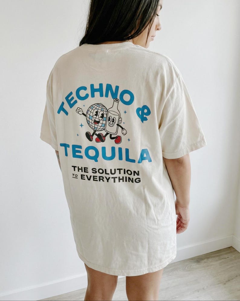 Puede incluir: Camiseta color crema con las palabras "TECHNO & TEQUILA" en azul, junto con un dibujo animado de una bola de discoteca y una botella de tequila. El texto "THE SOLUTION TO EVERYTHING" est&aacute; impreso debajo en negro.