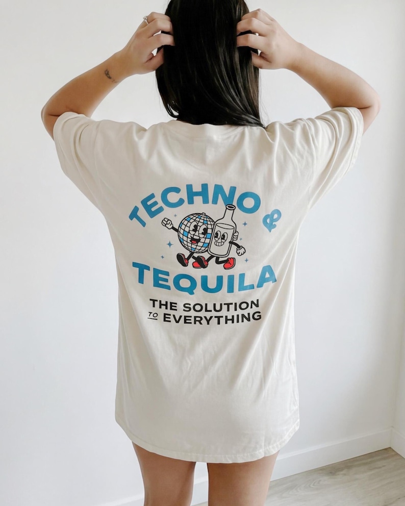 A girl with dark hair wearing a cream shirt. She is facing away from the camera. On the back of the shirt is a cartoon globe and tequila bottle walking together. the main text says “TECHNO & TEQUILA” with sub-text reading “THE SOLUTION TO EVERYTHING”