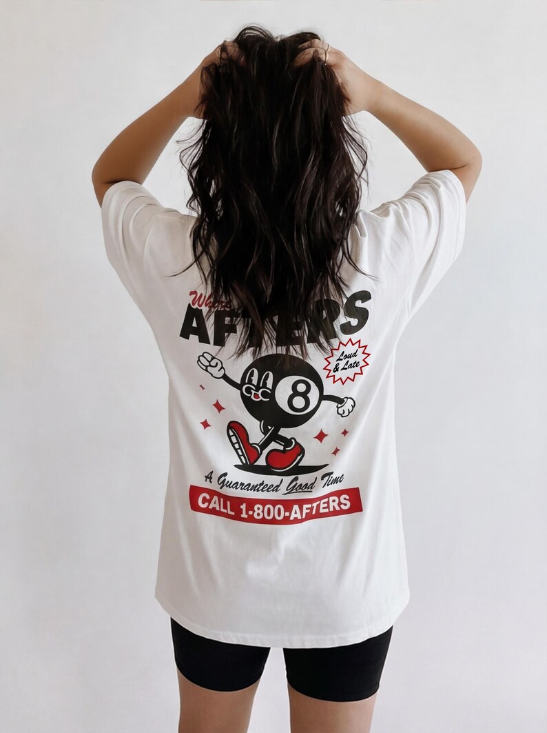 May include: White t-shirt with a graphic on the back featuring a cartoon eight ball character with red shoes and arms outstretched. The text reads "Wants AFTERS" and "A Guaranteed Good Time CALL 1-800-AFTERS."