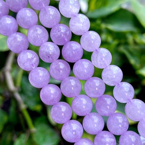 Puede incluir: Una hebra de cuentas de amatista lavanda, cada cuenta es redonda y lisa. Las cuentas están enhebradas en un cordón elástico transparente.