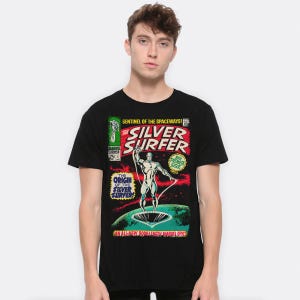May include: Black t-shirt with a comic book-style graphic of the Silver Surfer. The design includes the words "SILVER SURFER" prominently displayed, alongside text reading "SENTINEL OF THE SPACEWAYS!" and "AN ALL-NEW BOOK-LENGTH MARVEL EPIC."