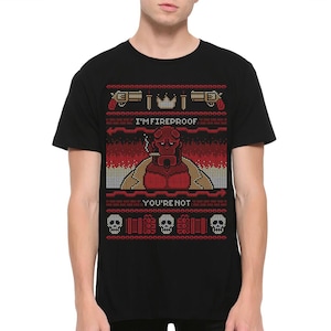 May include: Black t-shirt with a red and white pixelated design featuring a character with horns and the text "I'm Fireproof You're Not".