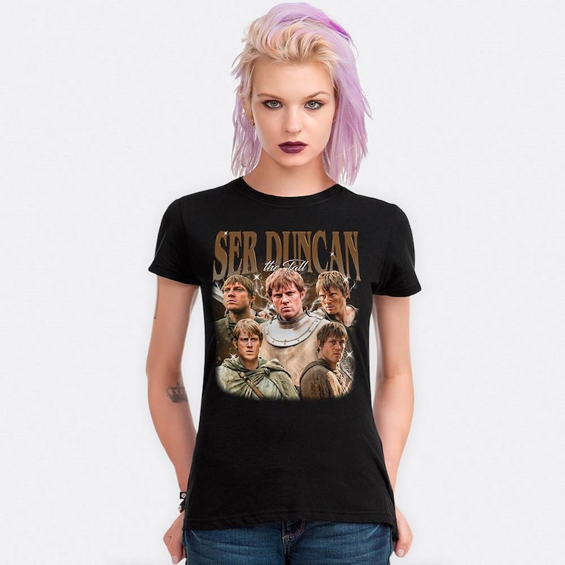 May include: Black t-shirt featuring a vintage-style graphic of a group of men with the text "Ser Duncan the Tall" in a distressed font. The graphic is centered on the shirt, with a faded, aged appearance.