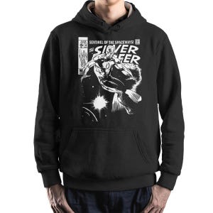 May include: Black hoodie with a white comic book-style illustration of the Silver Surfer. The graphic includes the text "Sentinel of the Spaceways!" and "The Silver Surfer". The hoodie has a front pocket and a drawstring hood.