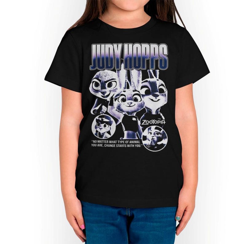 以下が含まれることがあります： 黒いTシャツ。映画「ズートピア」のジュディ・ホップスのデザイン。青と白の文字で「JUDY HOPPS」と書かれ、キャラクターの画像と「NO MATTER WHAT TYPE OF ANIMAL YOU ARE, CHANGE STARTS WITH YOU.」という引用句が描かれています。