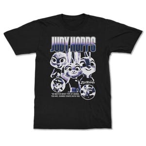 以下が含まれることがあります： 映画「ズートピア」のジュディ・ホップスのグラフィックがプリントされた黒いTシャツ。「JUDY HOPPS」の文字がグラデーションフォントでデザインされ、「どんな動物であっても、変化はあなたから始まる」という引用句が添えられています。