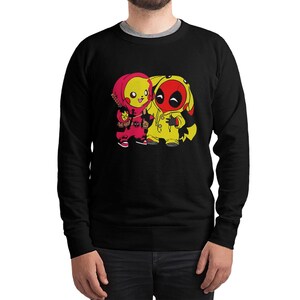 Puede incluir: Sudadera negra con un gr&aacute;fico de dos personajes de dibujos animados. Uno es amarillo y rojo, como Pikachu, y el otro es amarillo y rojo, como Deadpool. La sudadera tiene cuello redondo y mangas largas.