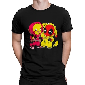May include: Black t-shirt featuring a graphic of two cartoon characters, one in a red outfit and the other in a yellow outfit. The red character is holding a sword. The yellow character has a red mask. The graphic is centered on the shirt.