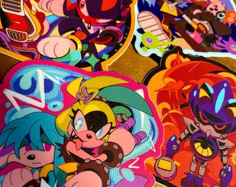 May include: A collection of colorful, die-cut stickers featuring various cartoon characters. The stickers showcase vibrant hues of blue, pink, yellow, and purple, with bold outlines and dynamic poses. The characters appear to be from a video game or animated series.