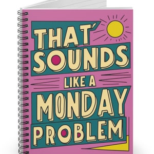 May include: A pink spiral notebook with the text "That Sounds Like A Monday Problem" in yellow and teal lettering. A yellow sun with rays is in the top right corner.
