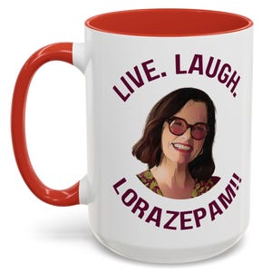 May include: White ceramic coffee mug with a red rim and handle. The mug features a graphic of a woman with glasses and the text "Live. Laugh. Lorazepam!" in a burgundy colour.