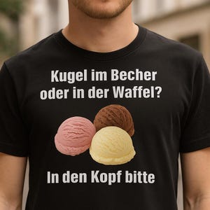 May include: Black t-shirt featuring three scoops of ice cream in pink, brown, and yellow. The shirt has the text "Kugel im Becher oder in der Waffel? In den Kopf bitte" in white, which translates to "Ice cream in a cup or waffle cone? In the head please."