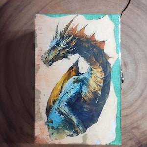 May include: A wooden box with a teal green lid and a blue and gold dragon illustration on the front.