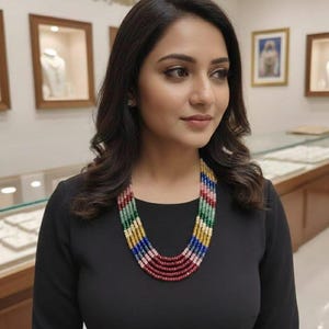 May include: A colourful, multi-strand beaded necklace featuring red, pink, yellow, green, and blue beads. The necklace is worn by a person in a black dress. A striking piece of jewellery.