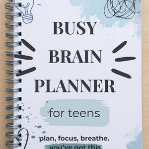 May include: A spiral-bound planner with the words "BUSY BRAIN PLANNER" in black font. The phrase "for teens" is below the title, with the words "plan, focus, breathe. you've got this" at the bottom. The cover has a light blue watercolor design and a lightbulb illustration.
