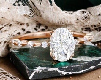 May include: A rose gold engagement ring with an oval-shaped diamond center stone and a delicate band of smaller diamonds.